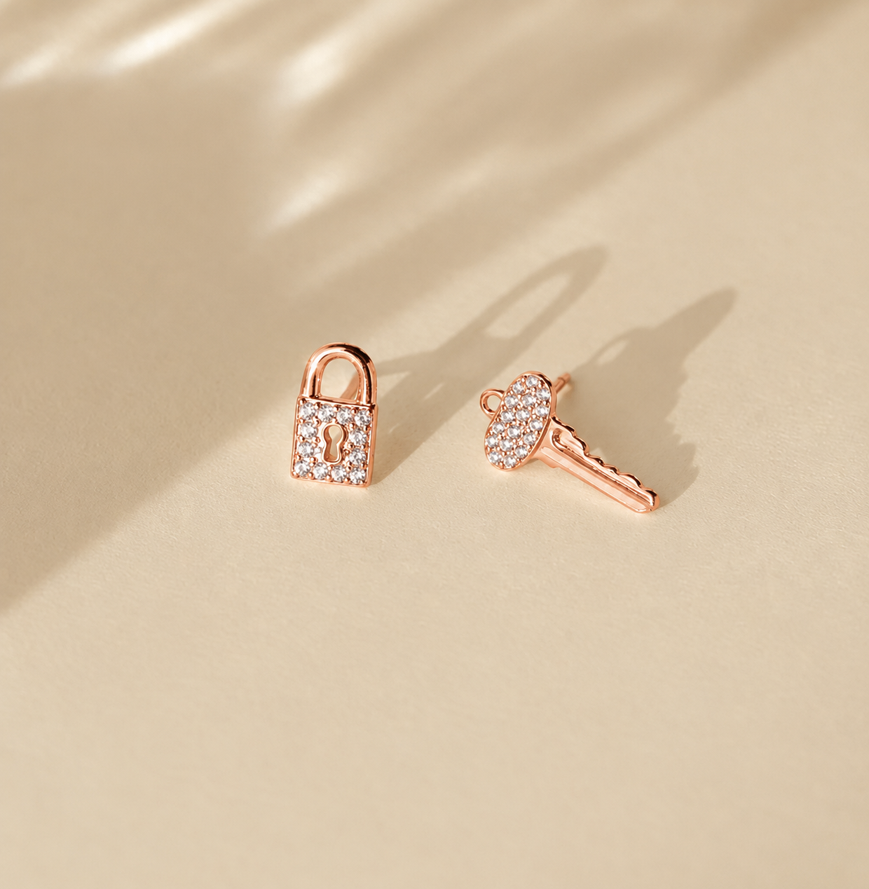 Rose gold lock-shaped earrings on a beige background